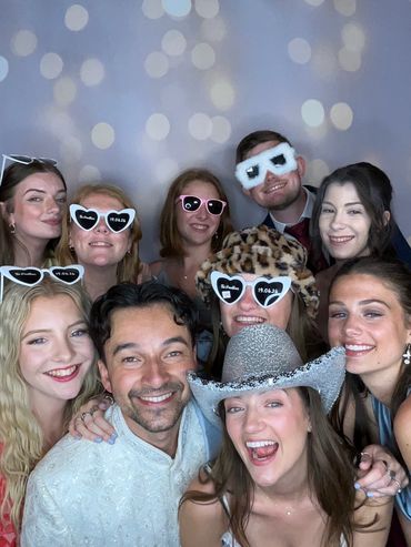 Group selfie with friends wearing playful novelty sunglasses and smiles.