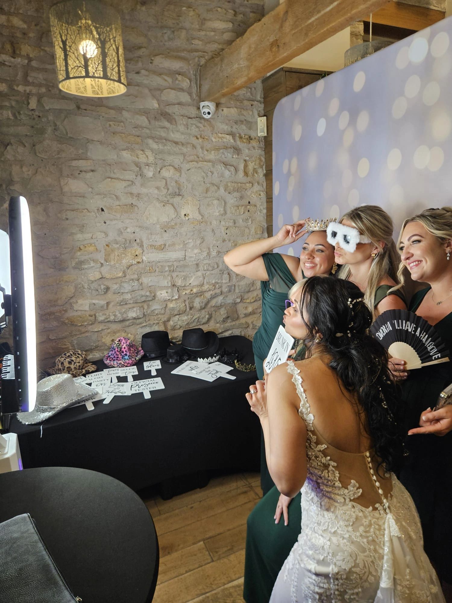 Group of women having fun at a photo booth, wearing props.