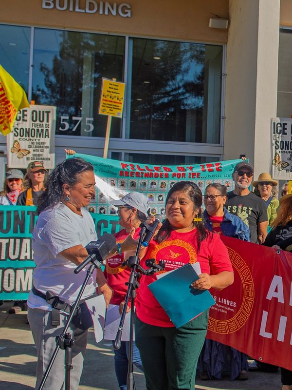 Protesters gathered outside a building holding signs and speaking.