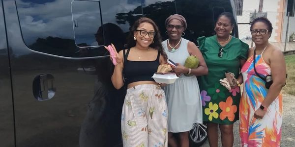 Four women smiling and posing by a black vehicle outdoors.