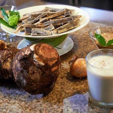Ingredients including dried fish, taro root, onion, and sauces on a kitchen counter.