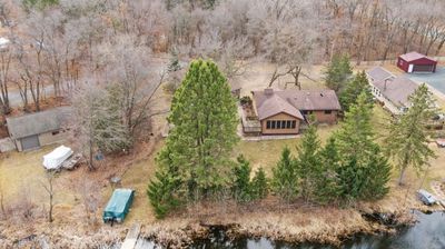 A riverside house surrounded by trees in late autumn.