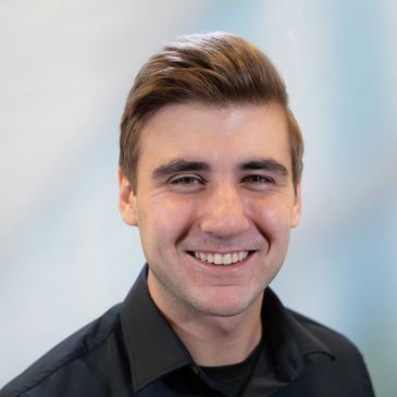 Smiling young man with neatly styled hair and black shirt.