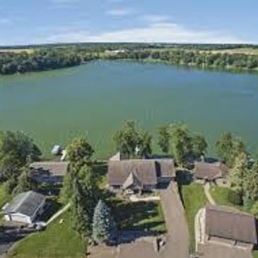 Aerial view of lakeside houses with a large body of water and greenery.