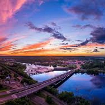Sunset over a river with bridges and a vibrant sky.