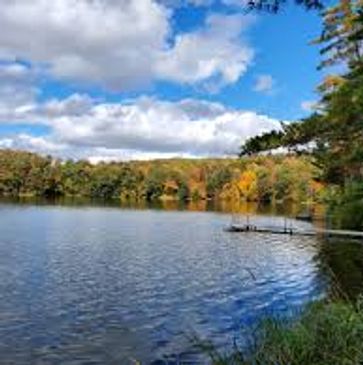 Serene lake with autumn foliage under a partly cloudy sky.