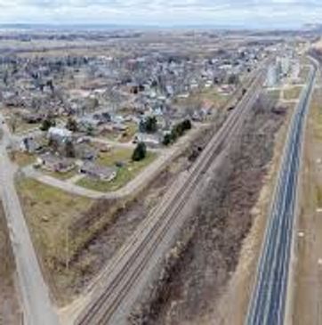 Aerial view of railway tracks running parallel to a highway near a residential area.