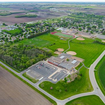 Aerial view of a small town with school, sports fields, and farmland.