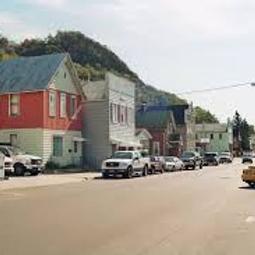 Small-town street with colorful houses and parked cars.
