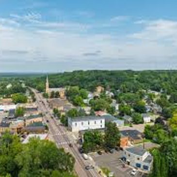 Aerial view of a small town with green trees and a church steeple.