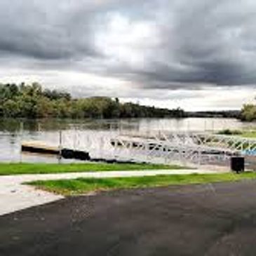 A cloudy sky over a calm river with a dock and greenery.
