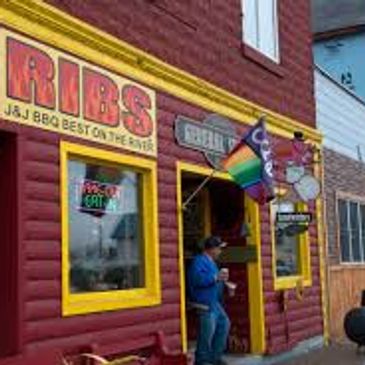 Colorful BBQ restaurant exterior with a rainbow flag and a person outside.