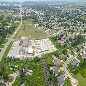 Aerial view of a suburban neighborhood and industrial area with roads and greenery.
