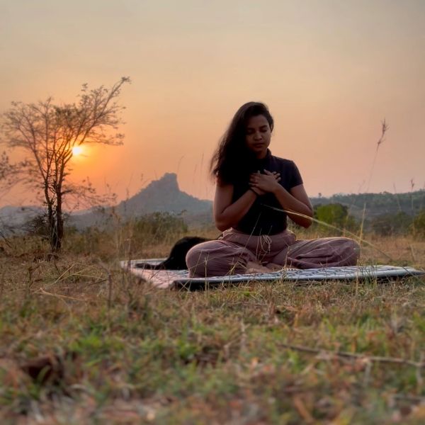 Woman meditating outdoors at sunset.