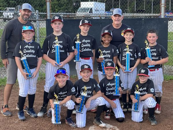 Youth baseball team proudly posing with trophies after a game.