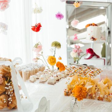 Elegant dessert table with colorful flowers and delicate treats.