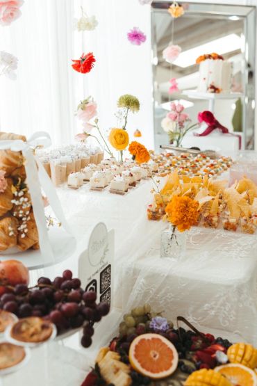 Elegant dessert table with flowers and fresh fruit at an event.