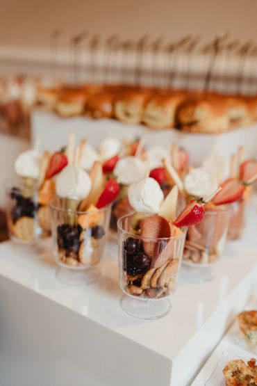 Elegant dessert cups with fruit, cookies, and meringue sticks.