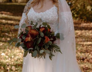 Bride’s fall bouquet with dark red roses, Orange Calla Lilies, Bronze Cremones, ferns and eucalyptus
