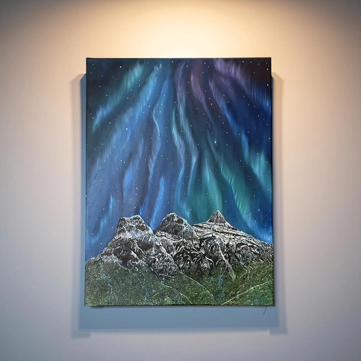 Painting of snowy mountains under a vibrant northern lights sky.