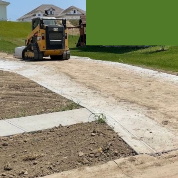 CAT skid loader on new driveway in Papillion Nebraska — Kinnan Scaping construction equipment damage