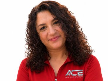 Smiling woman with curly hair wearing a red ACE shirt.
