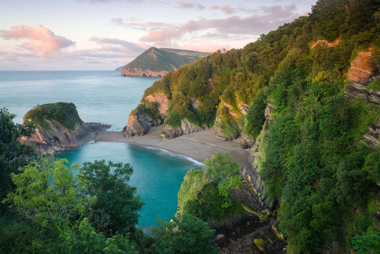 Secluded beach cove surrounded by green cliffs.