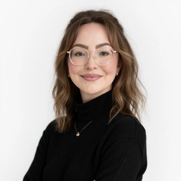 Smiling woman with glasses and wavy hair in a black turtleneck.