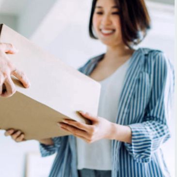 A smiling woman receiving a package at home.