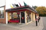 Small corner convenience store with red bench outside.