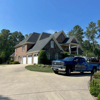 Large suburban house with a blue truck parked outside.