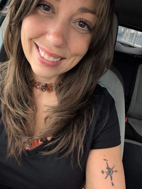 Smiling woman with a compass tattoo on her arm.