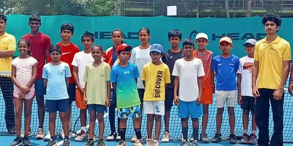 Group of kids and two adults on a tennis court.