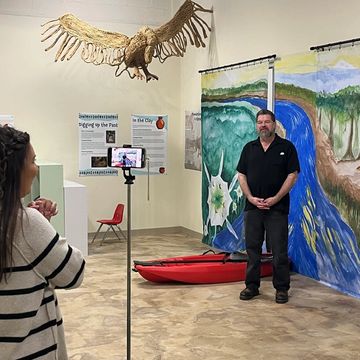 Stephen Criswell is filmed in front of a mural of the Catawba River in the “Clay and Play!” exhibit.