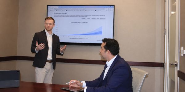 Two professionals discussing retirement analysis data in a conference room.