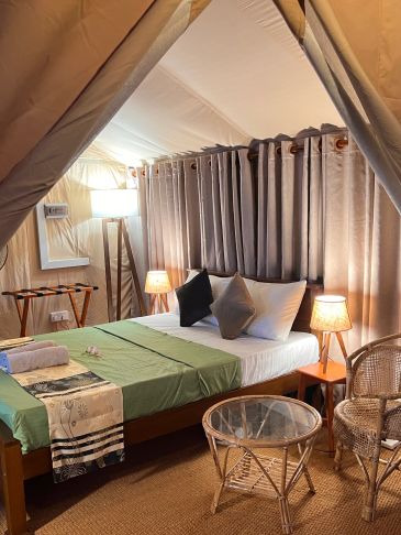 Cozy bedroom inside a tent with modern lighting and furniture.