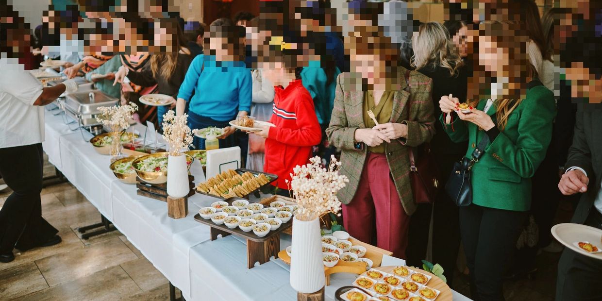 People serving themselves food at a buffet table during an event.