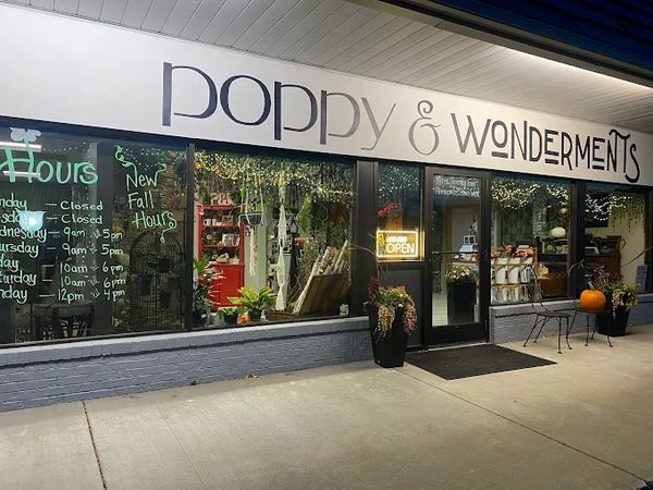 Front view of Poppy &amp; Wonderments shop with fall decorations and open sign.