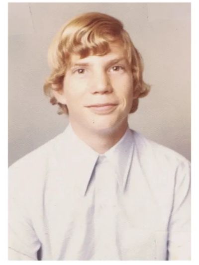 Young person with blond hair wearing a white shirt.
