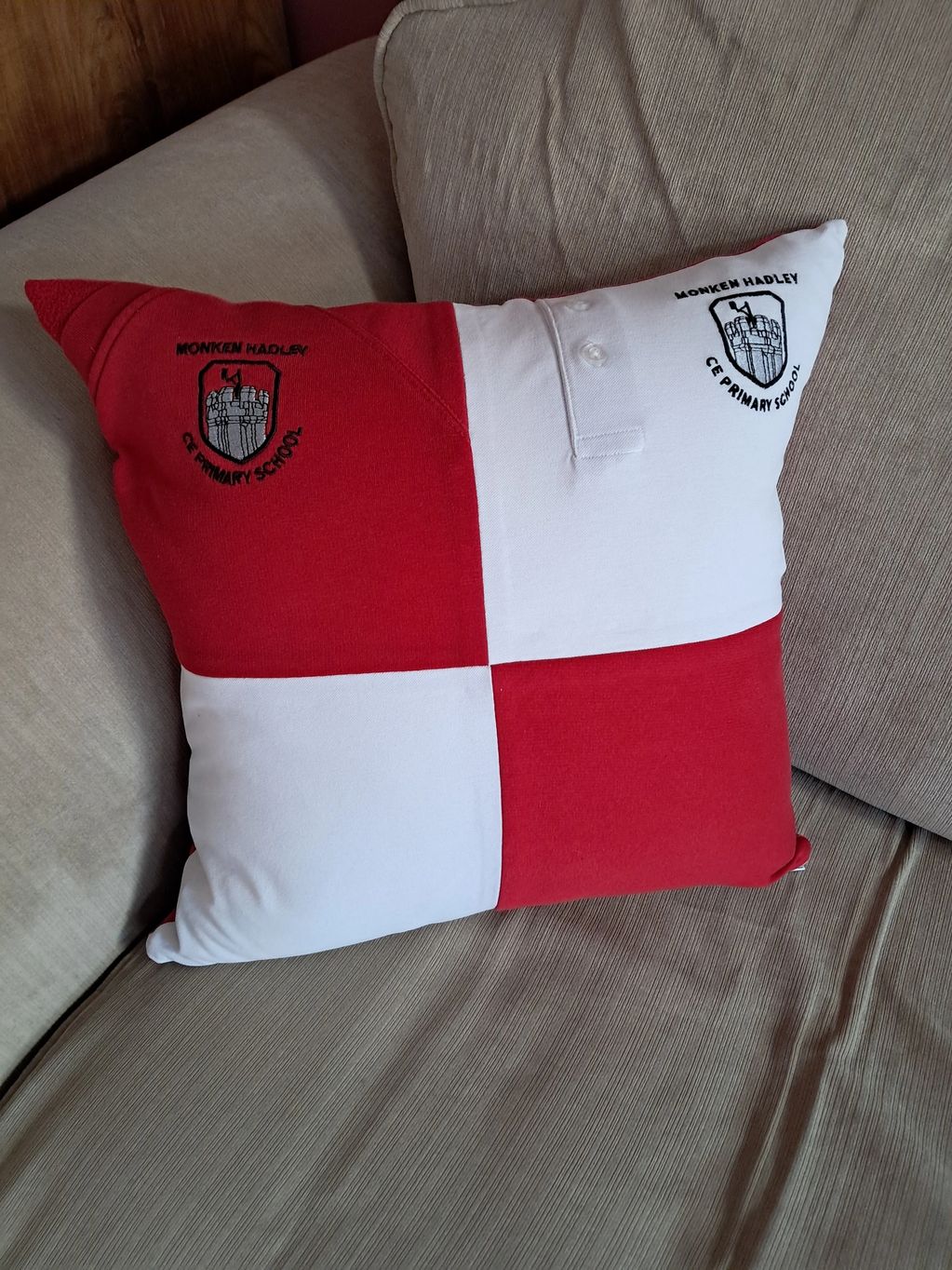 A white and red square cushion made from school uniform is placed on a sofa