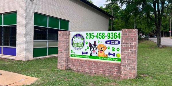 Signboard for Dog Days daycare and boarding with contact info and playful dog illustrations.