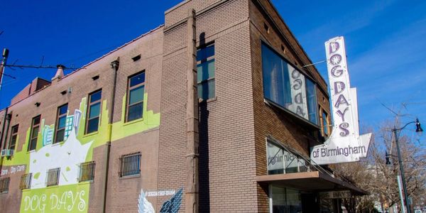 Brick building with Dog Days signage under a clear blue sky.