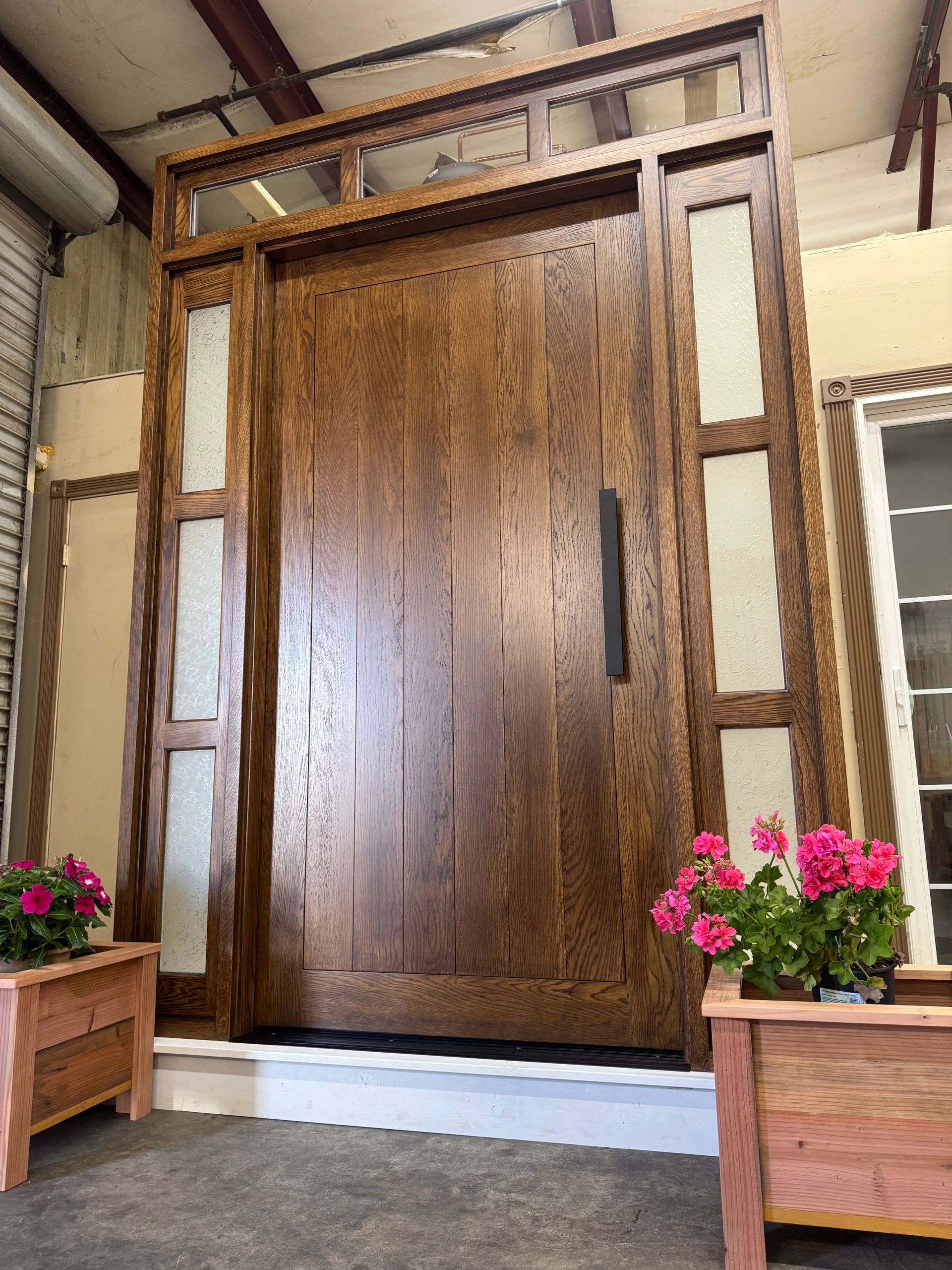 Large wooden door with glass panels and vibrant pink flowers.