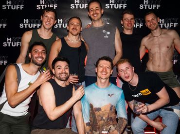 A group of nine friends smiling and posing at a Hot Stuff event.