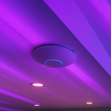 Ceiling-mounted circular device with blue light, surrounded by purple ambient lighting.