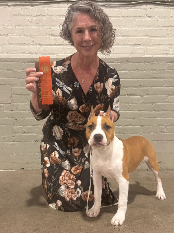 Woman with her dog holding an award ribbon.