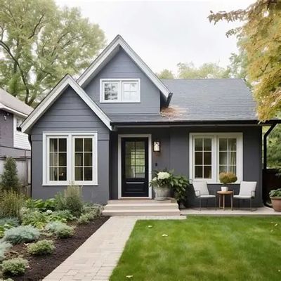 Charming gray house with white trim and a cozy front porch seating area.