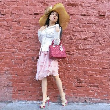 Woman in pink skirt by red brick wall