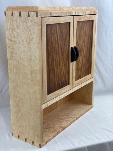 wall mounted cabinet made from birds eye maple with two doors and pulls made from ebony