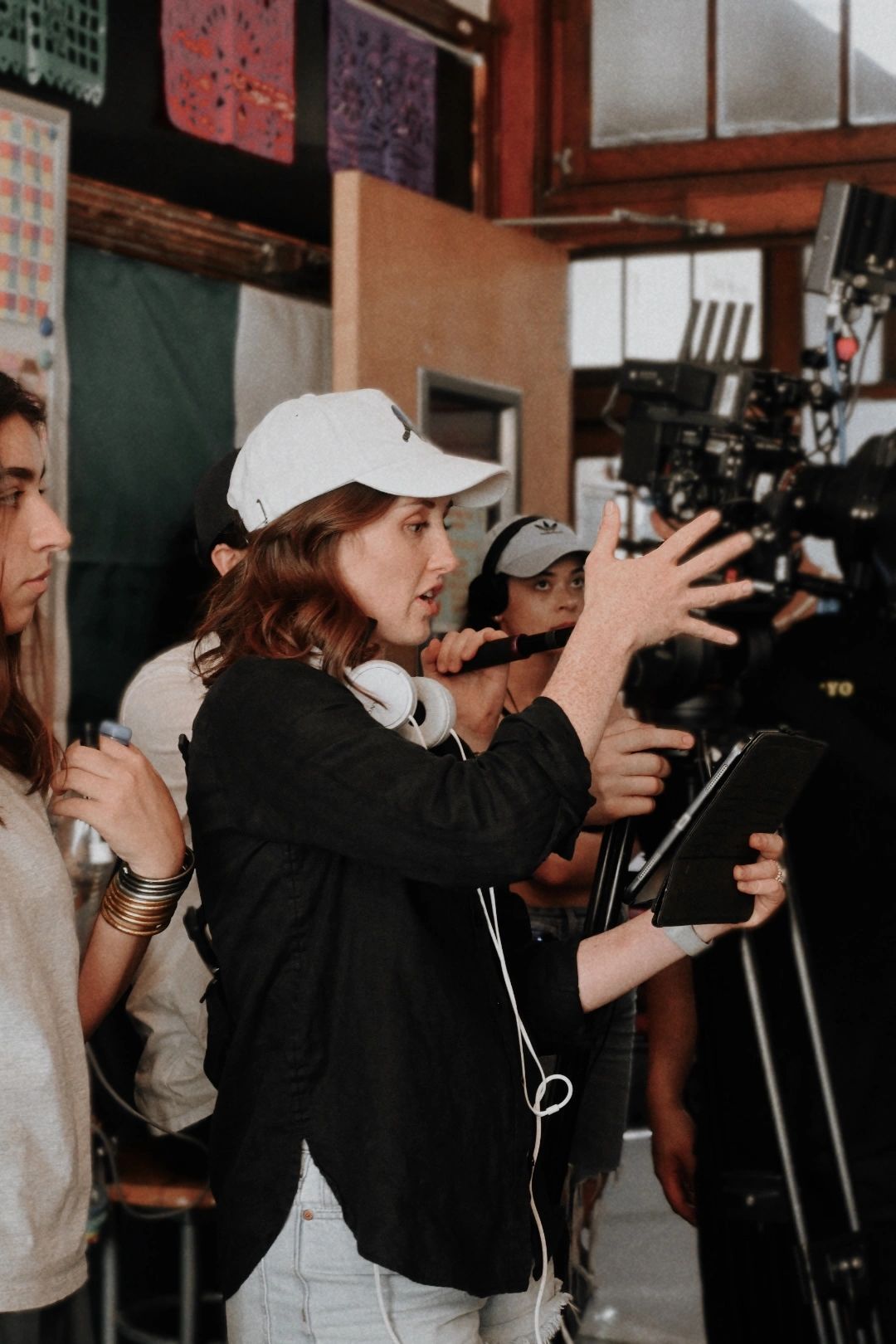 Woman directing a film shoot with camera crew.